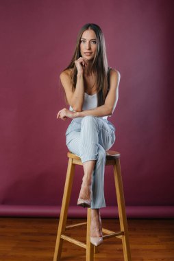 Stüdyoda sandalyede poz veren güzel seksi kız. Moda.