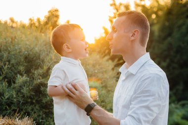 Baba ve oğul gün batımında parkta yürüyorlar. Mutluluk. Aşk