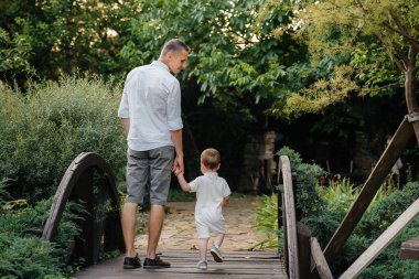 Baba ve oğul gün batımında parkta yürüyorlar. Mutluluk. Aşk