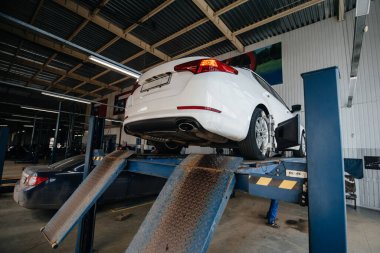 Benzin istasyonundaki asansörde egzoz sistemini teşhis etmek için yükseltilmiş araba. Servis İstasyonu