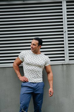 Sportif bir adam gri bir duvarın yanında duruyor. Yaşam biçimi