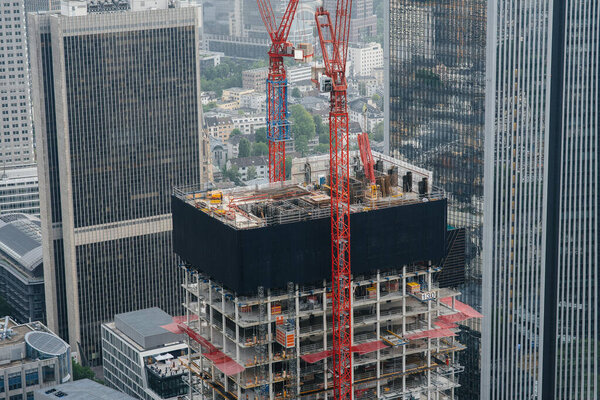 Construction of a modern high-rise skyscraper with cranes in the center of the metropolis. Construction