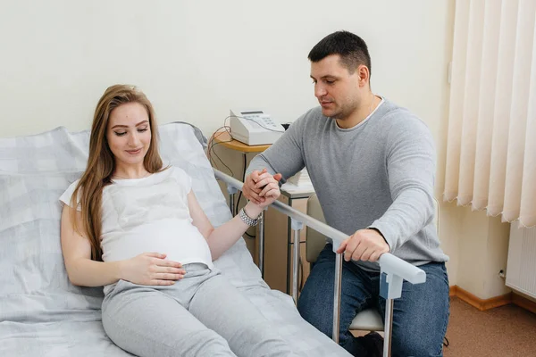 Pregnant girl in the clinic for consultation with the future father. Medical examination