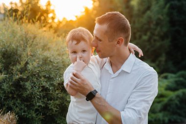 Baba ve oğul gün batımında parkta yürüyorlar. Mutluluk. Aşk