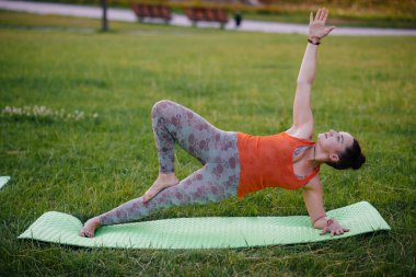 Gün batımında parkta yoga yapan genç bir kız. Sağlıklı yaşam tarzı