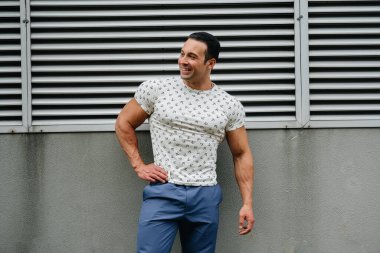 Sportif bir adam gri bir duvarın yanında duruyor. Yaşam biçimi