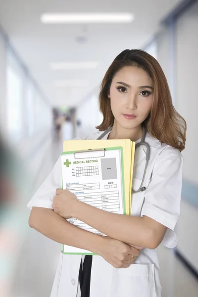 Female doctor holding blank medical record with hospital walkway