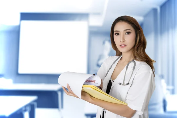 Médico femenino sosteniendo carpeta con fondo azul de reunión roo — Foto de Stock