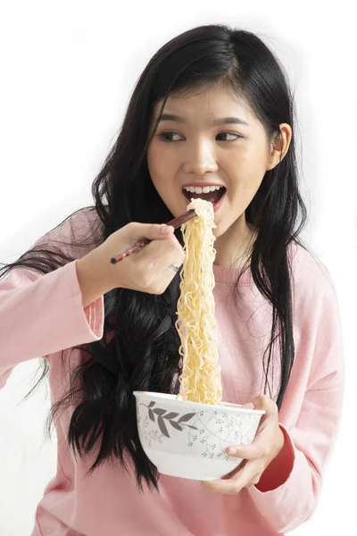 白い背景にインスタントラーメンを箸で口の中に押し込みながら食事を楽しむ女の子 — ストック写真