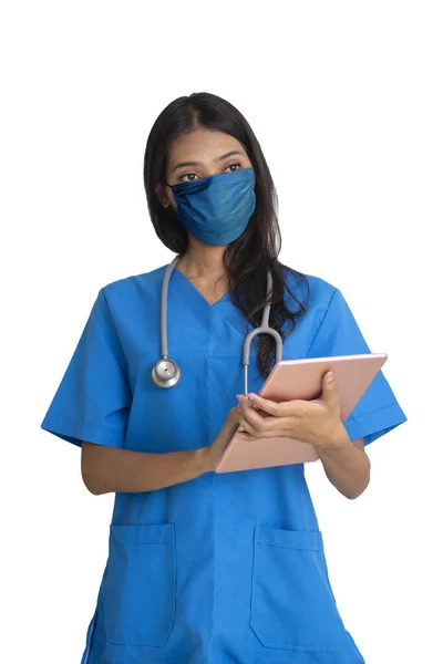 Female doctor wearing mask holding digital tablet in hands on white background.