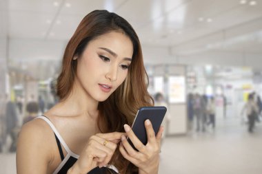 Kalabalığın bulanık geçmişiyle çevrimiçi bağlantı kurmak için akıllı telefon kullanan bir kadın.