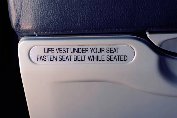 Safety sign on a commercial aircraft, indicating to fasten seat belt when seated.