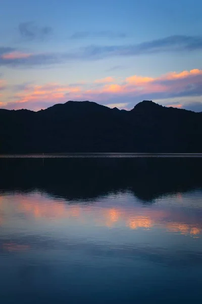 蔚蓝的暮色天空和漆黑的群山映衬着平静的湖水 — 图库照片