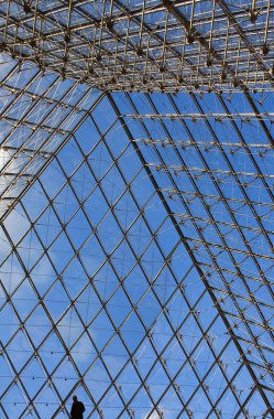 Modern cam ve metal yapılar, mavi bulutlu gökyüzüne karşı yalnız bir siluet oluşturur..