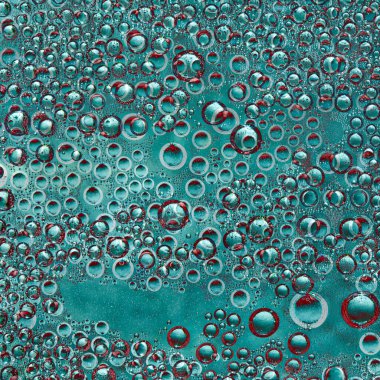 Kırmızı haleli farklı çaplı turkuaz renkli küreler turkuaz bir arka planda rastgele yer almaktadır. Boşluk soyutlaması.