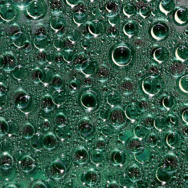 Farklı çaplarda yeşil şeffaf küreler ve yansımaları rastgele siyah bir arkaplanda yer alıyor. Boşluk soyutlaması.