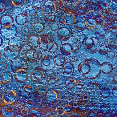 Farklı çaplara sahip çok renkli halkalar kahverengi-mavi arka planda yer almaktadır. Soyut fantezi.