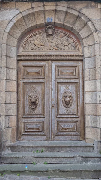 Французские двери: хорошо сохранившиеся и отреставрированные богатые двери главного дома: скульптурный лев в дубе, верхний деревянный колокол и другие скульптурные инструменты. Средневековый каменный каркас Saint Malo, France 17-9-19 — стоковое фото