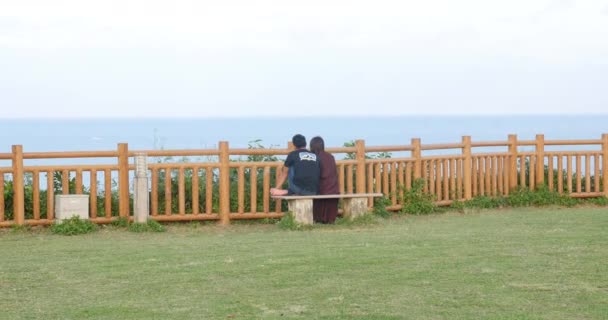 Cute couple sited on a bench looking at the sea at Cape chinen Okinawa, Japan. 20-1-20 This Park is a quiet place located on a hill, perfect for relaxing and whiling away the time. — Stock Video
