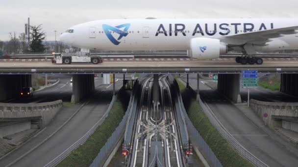 Air Austral Plane and CDG VAL tramway in Charles de Gaulle airport, Roissy, France, 5.2.2020 the cars driving on left side makes that shot contain 3 ways of transportation : road, rail and air — Stockvideo