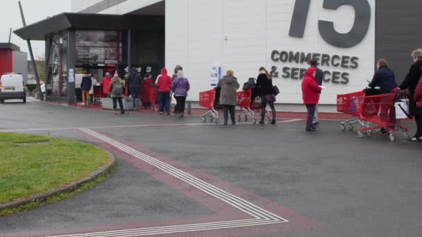 Kryzys konawirusowy we Francji: długa kolejka ludzi czekających na wejście do supermarketu, aby kupić żywność. kolejka od parkingu do wejścia. Francuzi przygotowują tygodnie izolacji w domu. Angers, Francja, 16.3.20 — Wideo stockowe