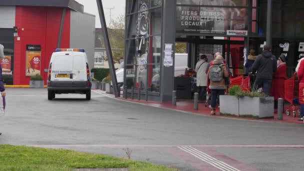Criza Covid-19: Masina de politie a orasului parcata in fata intrarii in supermarket. revolte și lupte care se întâmplă să cumpere alimente linie de așteptare foarte lungă de francezi bătrâni care pregătesc săptămâni de izolare la domiciliu. Angers, FRANȚA, 16.3.20 — Videoclip de stoc