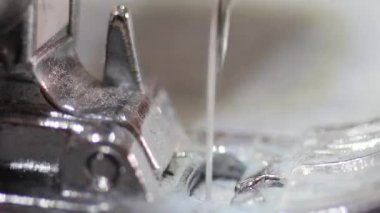 Dikiş makinesinin makro mekanik iğne dikiş kumaşı. Basınçlı ayak, dikiş makineleriyle makineden beslenen kumaşı düz tutmak ve dikmek için kullanılan bir eklentidir..