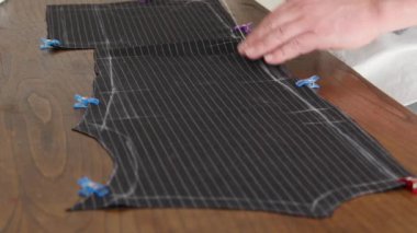 Bir terzinin elleri dikiş ipliği ile yüksek İtalyan terzi yünü kumaşından bir ceket dikiyor. Bu terzi atölye moda stüdyosunda kumaş dikiyor. 4K 'yı kapat.