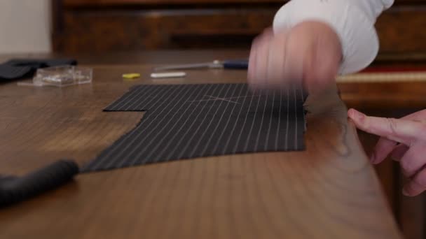 Profesjonalny krawiec przenoszący oznaczenia wzorców i rysujący na czarnej tkaninie w paski poprzez stukanie w tkaninę. ślady kredy zostaną przeniesione po tym procesie.. — Wideo stockowe