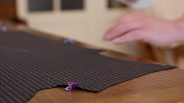 Średni strzał zajęty Stylista męski garnitur maker krawiec przenosząc szablon na wzór tekstylny, stukanie proces tworzenia odzieży. — Wideo stockowe
