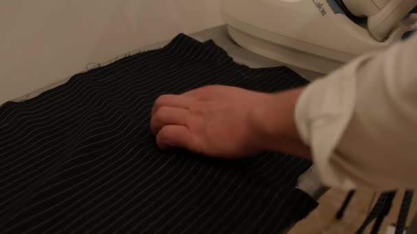 Tailor ironing a piece of black material on the table in the bespoke suit making process. Close-up of tailor's work — Stock Video