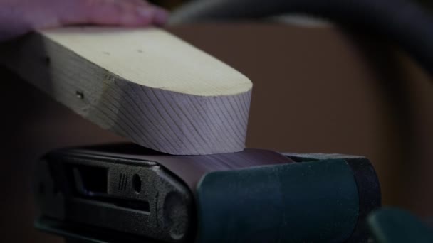 Tukang kayu yang bekerja dengan sabuklistrik di papan kayu. Ini pekerjaan sanding pada sepotong kayu adalah salah satu langkah dalam proses membuat furnitur kabinet kayu. Pengrajin Cabinetmaker. — Stok Video
