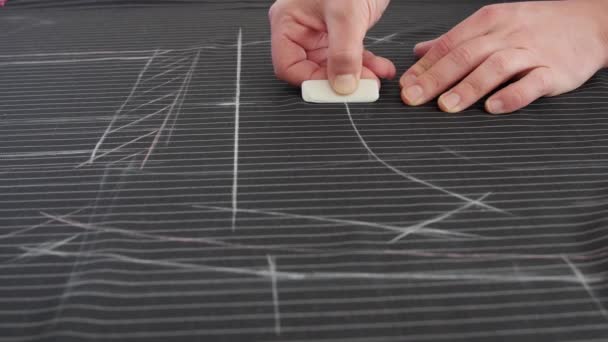Diseñar ropa, aplicar una plantilla a un tejido textil, prepararse para cortar y coser. Un sastre dibuja una línea con tiza en un paño textil con tijeras profesionales y una regla , — Vídeo de stock