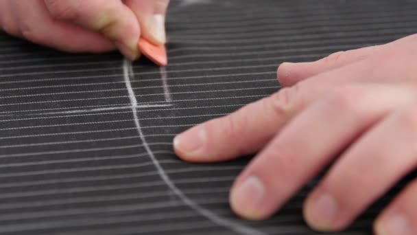 Tailor hand working with sewing pattern in atelier. man tailor creating line, working with chalk on personal desk, developing embroidery pattern on striped black fabric — Stock Video