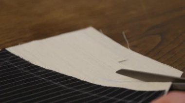 Terzi atölyedeki masada makasıyla kumaş kesiyor, terzilik sürecini kapatıyor. Yakından, Terzi çalışıyor. Yeni bir paltoya kumaş kesiyor.