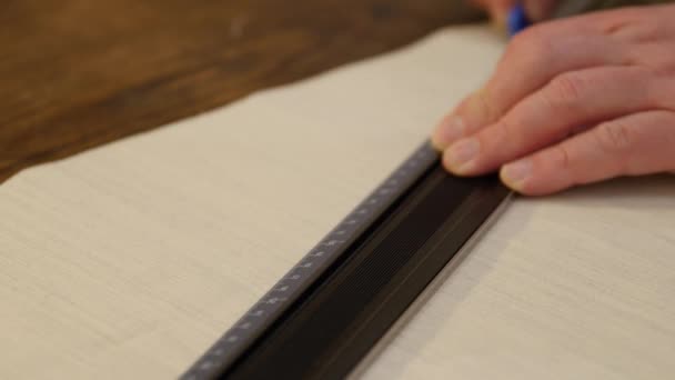 Tailor hands working with measure bar. Designing clothes, applying a template to a textile fabric, preparing for cutting and sewing. A tailor draws a line with chalk on a textile cloth — Stock Video