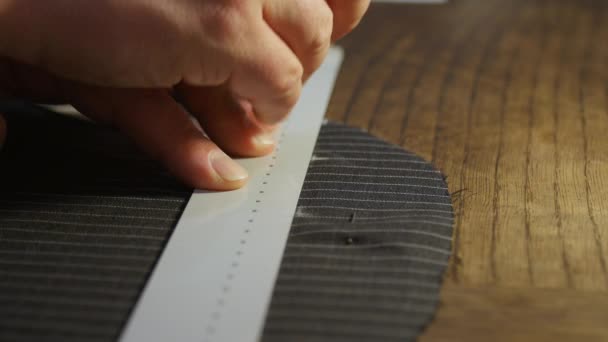 Κλείσιμο εξειδικευμένου ράφτη που εργάζεται στο ατελιέ: σήμανση και μέτρηση υφάσματος με τα χέρια, ενώ φτιάχνει τσέπες και προσόψεις ρούχων — Αρχείο Βίντεο