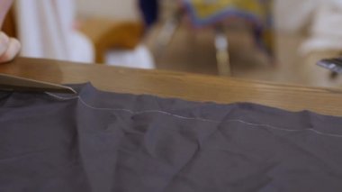 Terzi tasarımcı elleri astarlı kumaş kesiyor. Bir astar giysi üzerindeki baskıyı azaltır, çizgili giysinin kullanışlı ömrünü uzatır. Pürüzsüz bir astar bir ceketin ya da ceketin üzerinden kaymasına izin verir.