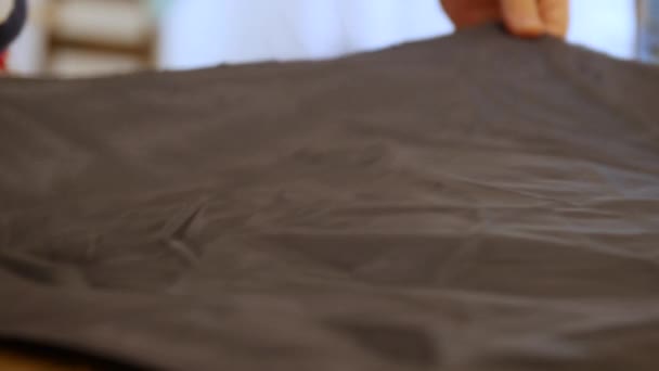 Чоловік Дизайнер наносить зморшкувату тканину на дерев'яний стіл. При шитті та пошитті вагонка є внутрішнім шаром тканини, хутра або іншого матеріалу, вставленого в одяг костюм і смокінг — стокове відео