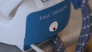 Yakışıklı erkek elleri çalışıyor ve buhar ütüsünü ısıtıyor.