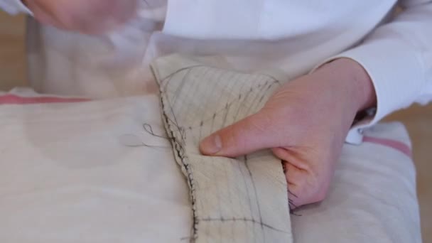 Modedesignerin näht mit der Hand einen Kragen. Tamponstiche sichern zwei oder mehr Lagen Stoff zusammen und verleihen den Lagen mehr Festigkeit; kleinere und dichtere Stiche schaffen mehr Festigkeit — Stockvideo