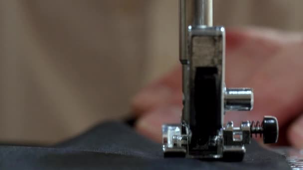 Ραπτομηχανή Βελόνα σε κίνηση: Κοντινό πλάνο της βελόνας ραπτομηχανή κινείται γρήγορα πάνω και κάτω. Ο ράφτης ράβει μαύρο ύφασμα στο εργαστήριο ραπτικής κατά τη διάρκεια της διαδικασίας της ραπτικής κοστούμι ύφασμα. — Αρχείο Βίντεο