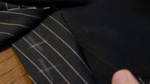 Close up shot of professional Tailor sewing vent with needle and thread. striped black wool suit fabric — Stock Video
