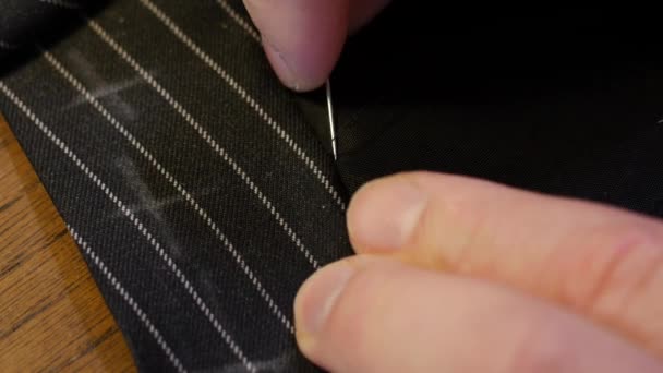 Tailor needle : hand of a young seamstress sewing a cloth tailoring vent according to tailors tradition. The dressmaker uses perfectly needle and thread to sew traditional and concept style — Stock Video