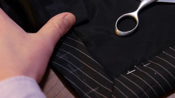 Любительский портной швейный вентилятор с иголкой и ниткой на полосатой черной шерстяной ткани костюма — стоковое видео
