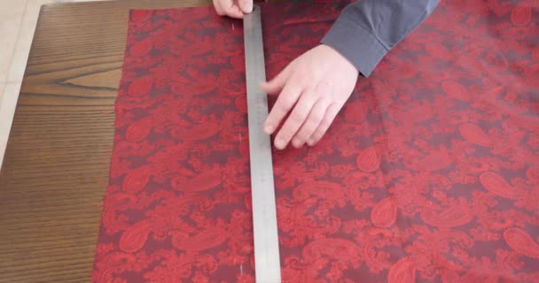 Modeontwerper werkt op tafel. Hand van Kaukasische traditionele mannelijke kleermaker tekening patroon op papier in de studio. kostuummaker met meetlint op schouders die in de werkplaats werken. — Stockvideo