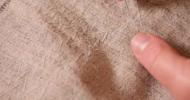 Erkek, kumaş fabrikasında nakış işliyor. İşçi takım elbisesiyle nakış işlemeye hazırlanıyor. Erkek el nakış işlemek için bir iğne, insan eline tutturulmuş bir iğne tutuyor.