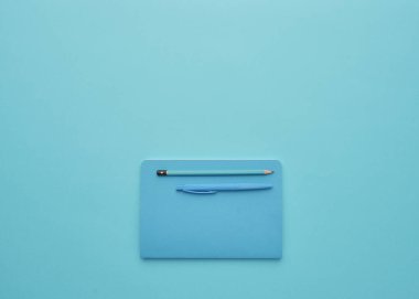 Mavi arka planda bir defter, okula geri dönüş, öğrenci aksesuarları, bir yazıt için boş alan, düz uzan