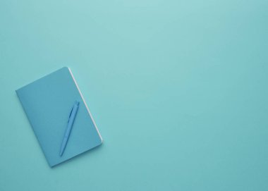 Mavi arka planda bir defter, okula geri dönüş, öğrenci aksesuarları, bir yazıt için boş alan, düz uzan