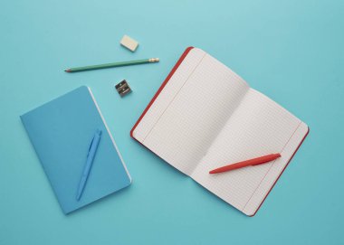 Mavi arka planda bir defter, okula geri dönüş, öğrenci aksesuarları, bir yazıt için boş alan, düz uzan